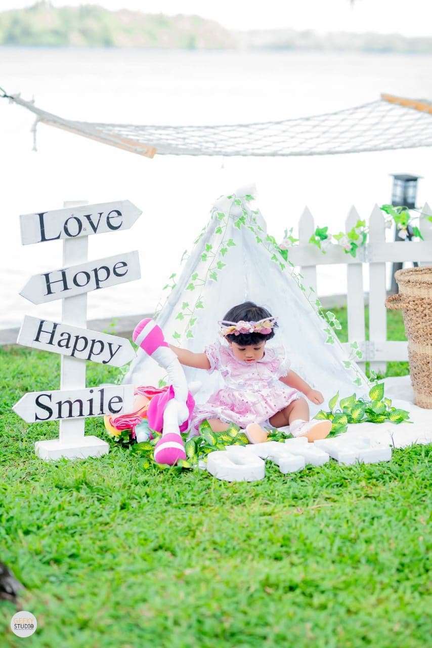 Baby girl playing in decorated tent area at AquaTrek lakeside birthday celebration