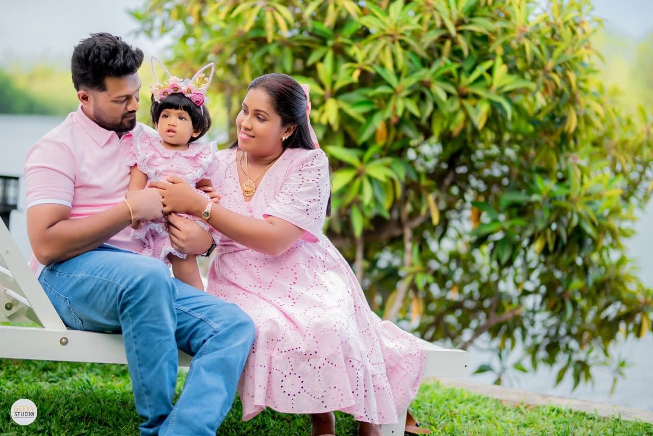 Parents with baby girl sitting on white bench by Rathgama Lake during AquaTrek birthday event